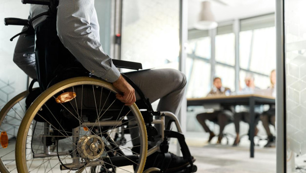 Unrecognizable male candidate in a wheelchair entering the office for a job interview.