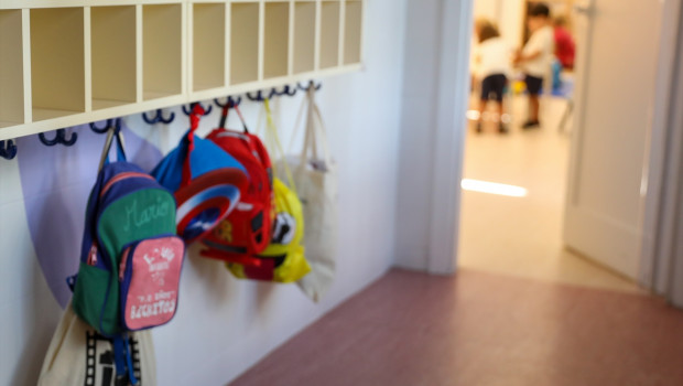 Varias mochilas en una percha de un aula infantil