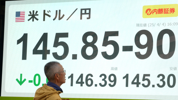 Un hombre mira una pizarra electrónica que muestra el precio de intercambio del yen japonés frente al dólar estadounidense en una calle de Tokio el 4 de abril de 2025