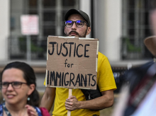 Un hombre sostiene una pancarta durante una vigilia por los 53 migrantes que murieron en un camión en Texas