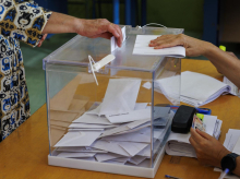 Una mujer introduce su voto en una urna en un colegio electoral del centro de Sevilla