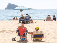 Numerosas personas se bañan y toman el sol en la playa de Poniente, Benidorm, Alicante