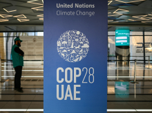 Un hombre cerca de un cartel de la COP28 en una estación de metro de Dubái