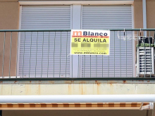 Un balcón con un anuncio de alquiler de una vivienda