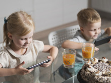 Niños comiendo con el móvil en la mano