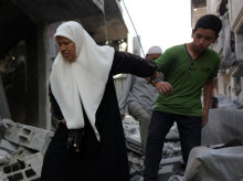 Un niño ayuda a una anciana palestina a caminar entre los escombros