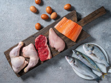 Healthy protein source food meat, eggs and fish: chicken, beaf, salmon, seabass, mackerel and sea bream on a cutting board in a gray kitchen table background