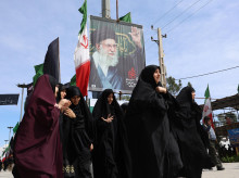 Mujeres iraníes caminan cerca de un cartel del difunto líder supremo iraní, el ayatolá Ali Khamnei, durante el funeral de las víctimas del conflicto entre Irán, Israel y Estados Unidos, en el cementerio Behesht Zahra, al sur de Teherán, Irán,