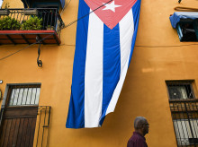 Un hombre pasa junto a una bandera cubana colgada en la fachada de una casa en La Habana