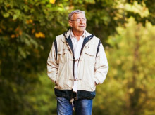 Happy senior man walking and relaxing in park