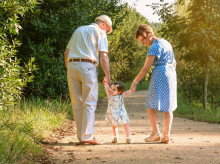 Back view of grandparents and baby grandchild walking on a nature path