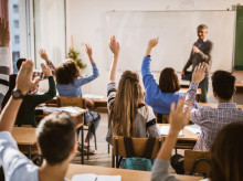 Estudiantes levantando las manos de una clase