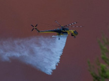 Un helicóptero de extinción de incendios arroja agua sobre un incendio forestal en la zona de Porto Germeno, a unos 70 kilómetros (45 millas) al noroeste de Atenas
