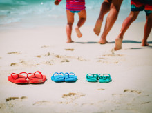 Imagen de archivo de unos niños corriendo por una playa, junto a unas chanclas