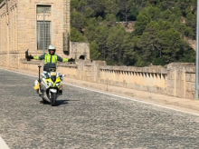 Un agente circula sobre su moto con los brazos en cruz