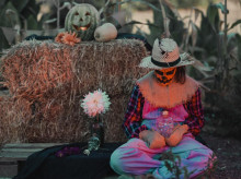 Una chica disfrazada de espantapájaros, rodeada de calabazas de Halloween