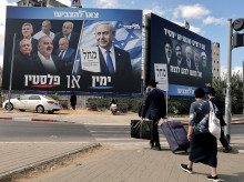 Los peatones cruzan una calle frente a una pancarta (izquierda) con la imagen del primer ministro israelí Benjamin Netanyahu, del partido Likud, y miembros de la oposición, antes de las elecciones legislativas del país en Bnei Brak
