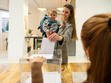 Una madre, junto a su bebé, introduce una papeleta en un colegio electoral