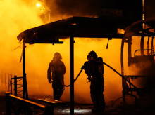 Los bomberos extinguen un autobús quemado durante los enfrentamientos entre los manifestantes y la policía antidisturbios