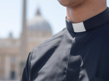 Un sacerdote con la basílica de San Pedro de fondo