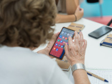 Una persona sostiene un teléfono móvil durante un curso de alfabetizacióin digital para personas mayores.