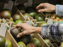 Una mujer eligiendo aguacate en el supermercado