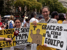 Dos jóvenes sostienen carteles con mensajes para el Santo Padre León XIV frente a la catedral de Barcelona