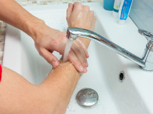 A man washes his hands up to the elbows under the tap