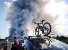 Bystanders watch as smoke rises from a fire at the Russian e-commerce firm Wildberries' logistics complexes in the town of Elektrostal outside Moscow on July 18, 2026. A Ukrainian drone attack on two logistics centres in Russia killed eight people and injured 24, officials said on July 18, 2026, when the Moscow region reported a new wave of drone strikes. Russian e-commerce firm Wildberries said its logistics complexes in Kotovsk and Elektrostal, in the Tambov and Moscow regions respectively, came under attack. One person was killed and 37 were injured at the Elektrostal warehouse, according to the region's governor, Andrei Vorobyov. (Photo by TATYANA MAKEYEVA / AFP)