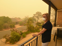 Una mujer, en un balcón, usa una máscara facial para protegerse contra un nivel muy peligroso de contaminación del aire