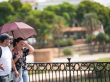Dos personas con sombrilla y ropa veraniega durante una jornada de intenso calor
