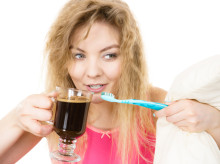 Happy woman holding toothbrush and coffee going to brush her teeth after hot drink.