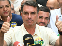 Brazil's right-wing senator and presidential candidate for the Liberal Party (PL) Flavio Bolsonaro gives thumbs up in front of Rio de Janeiro gubernatorial candidate Douglas Ruas (C, back), as he leaves a polling station after voting during the presidential election in Rio de Janeiro, Brazil, on October 4, 2026. Brazilians head to the polls deeply polarized in a nail-biting first-round presidential election and under the shadow of US President Donald Trump, who has backed conservative candidates in recent elections in Latin America. (Photo by MAURO PIMENTEL / AFP)