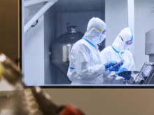 Científicos con trajes limpios usando tabletas digitales en experimentos en laboratorio