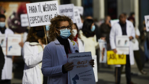 Una trabajadora sanitaria sostiene un cartel durante una concentración en la Puerta del Sol