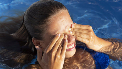 Niña frotándose los ojos en la piscina