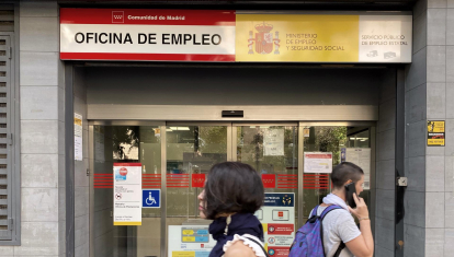 Dos personas pasean cerca de una oficina de empleo en Madrid.