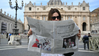 Una mujer lee L'Osservatore Romano con la noticia del nuevo Papa León XIV