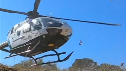 El helicóptero de la Guardia Civil tomando tierra junto a los moteros