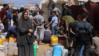 Palestinos intentan recoger agua en un campamento para desplazados en la ciudad de Gaza