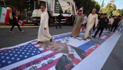 Iraquíes pisan una bandera estadounidense con el retrato del presidente Donald Trump durante una marcha en el distrito de Kadhimiya
