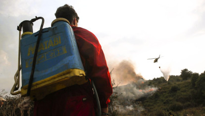 Un trabajador de extinción de incendios, este agosto, en León, contempla un helicóptero arrojando agua sobre las llamas