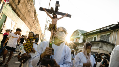 Una mujer saca un crucifijo con el cartel INRI por las calles de Filipinas