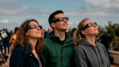 Imagen de tres personas con las gafas solares para contemplar el eclipse total.