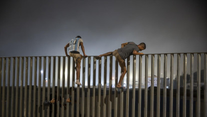 Varias personas saltan la valla que hace de frontera entre Ceuta y Marruecos.