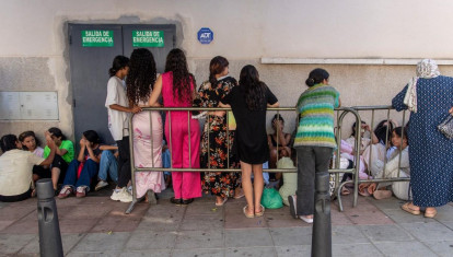 Menores inmigrantes aguardan frente a la sede de la Policía Nacional para iniciar los trámites de identificación y registro en el enclave español de Ceuta