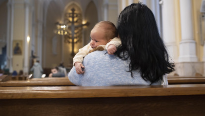 Una madre junto a su bebé, esperando que empiece la Eucaristía