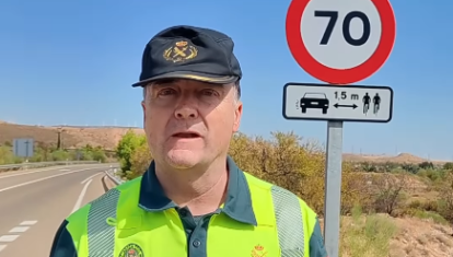 El agente explica la distancia lateral junto a una señal de carretera