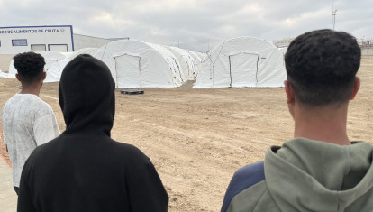 Tres inmigrantes junto al nuevo campamento, en el puerto de Ceuta