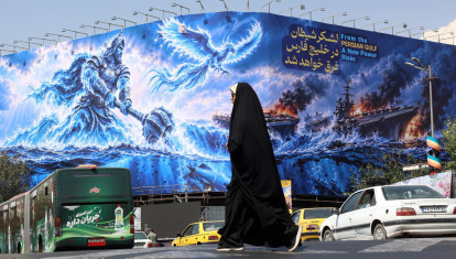 Una mujer iraní camina junto a una valla propagandista antiestadounidense en la plaza Enghelab de Teherán